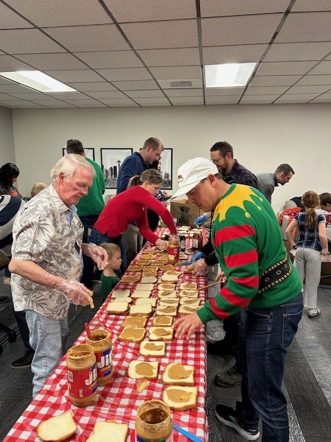 Volunteers assembling peanut butter and jelly sandwiches on a long table